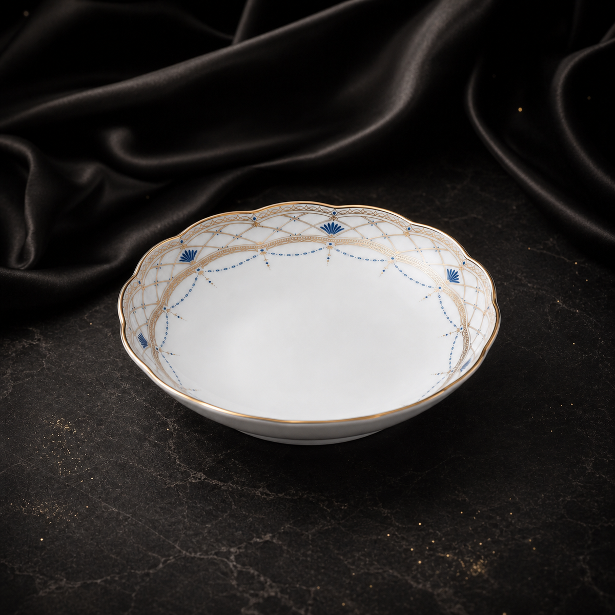 Front three-quarter view of the Valesse Azure fruit bowl showing its shallow depth, footed base and blue-and-gold rim.