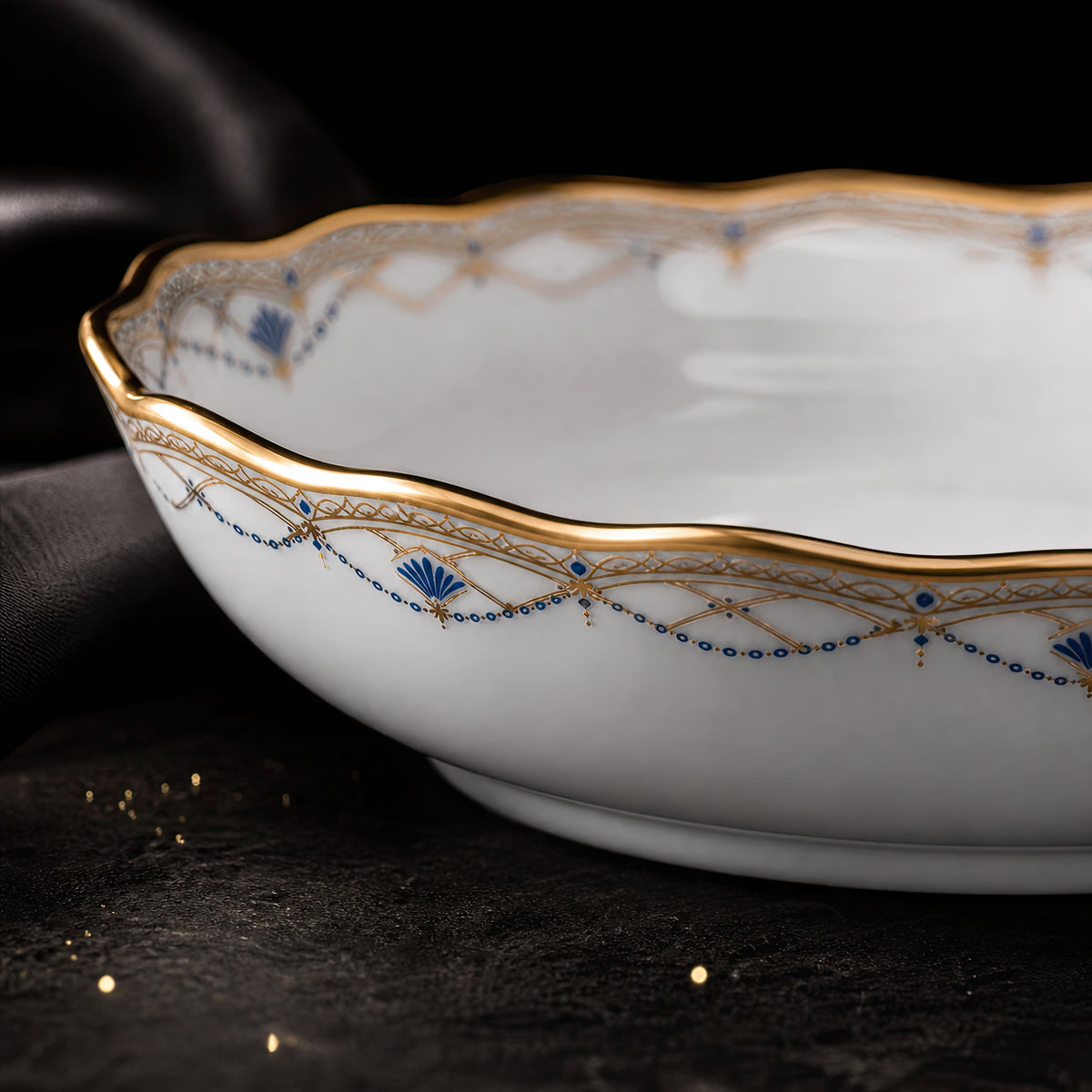 Side close-up of the Valesse Azure fruit bowl showing its gently curved depth, scalloped gold rim and blue border motifs.