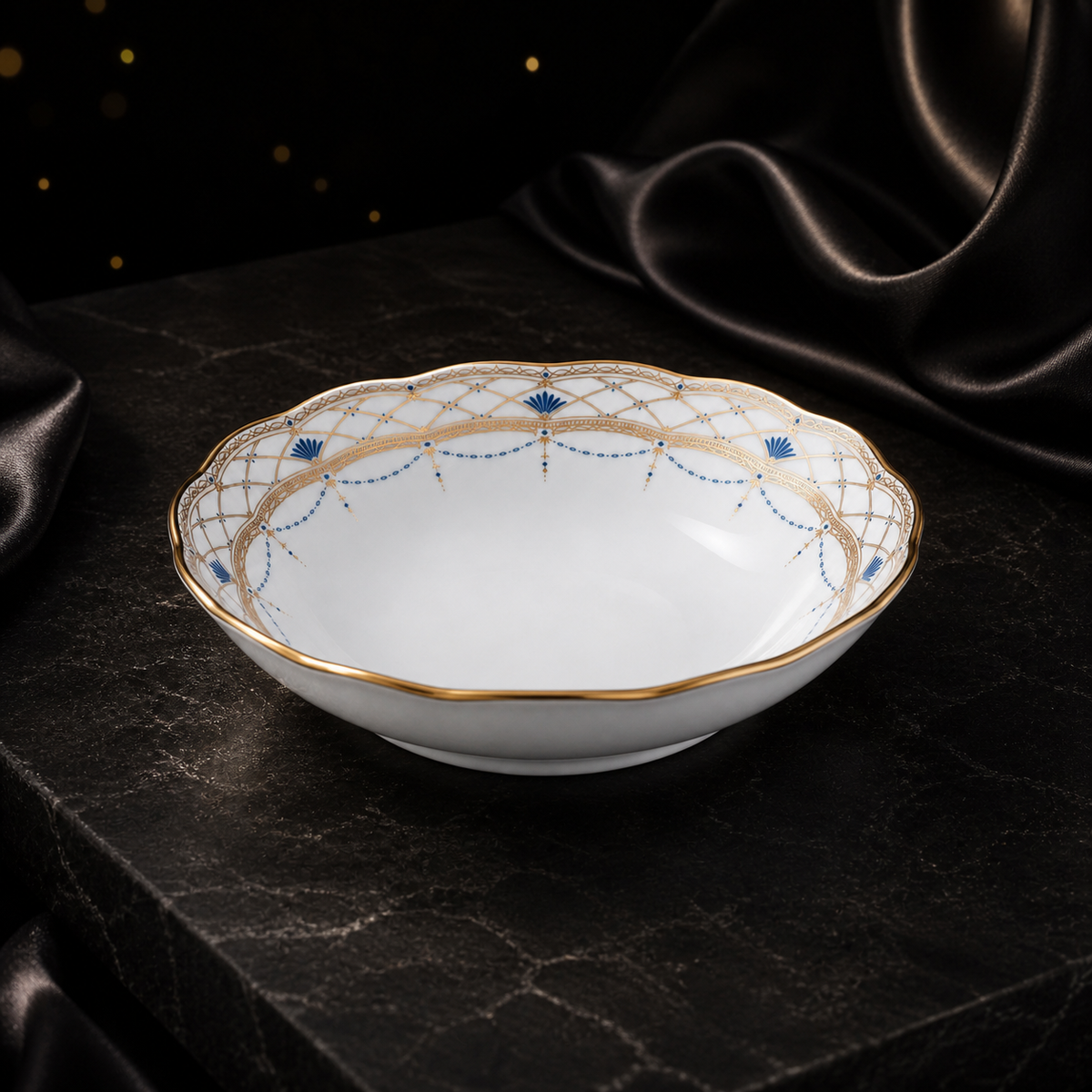 Three-quarter view of the empty Valesse Azure fruit bowl on a dark stone surface with black satin styling.