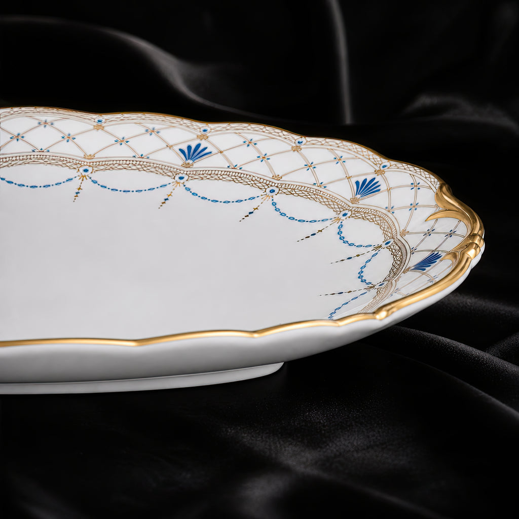 Low side close-up of the Valesse Azure 33 cm oval platter highlighting its raised rim and blue-and-gold ornament.
