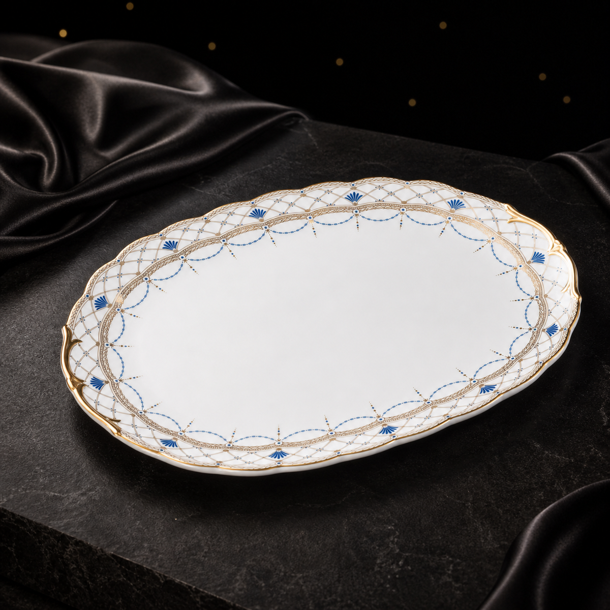Three-quarter view of the Valesse Azure oval platter on dark stone with black satin, emphasizing its elongated shape and decorative rim.