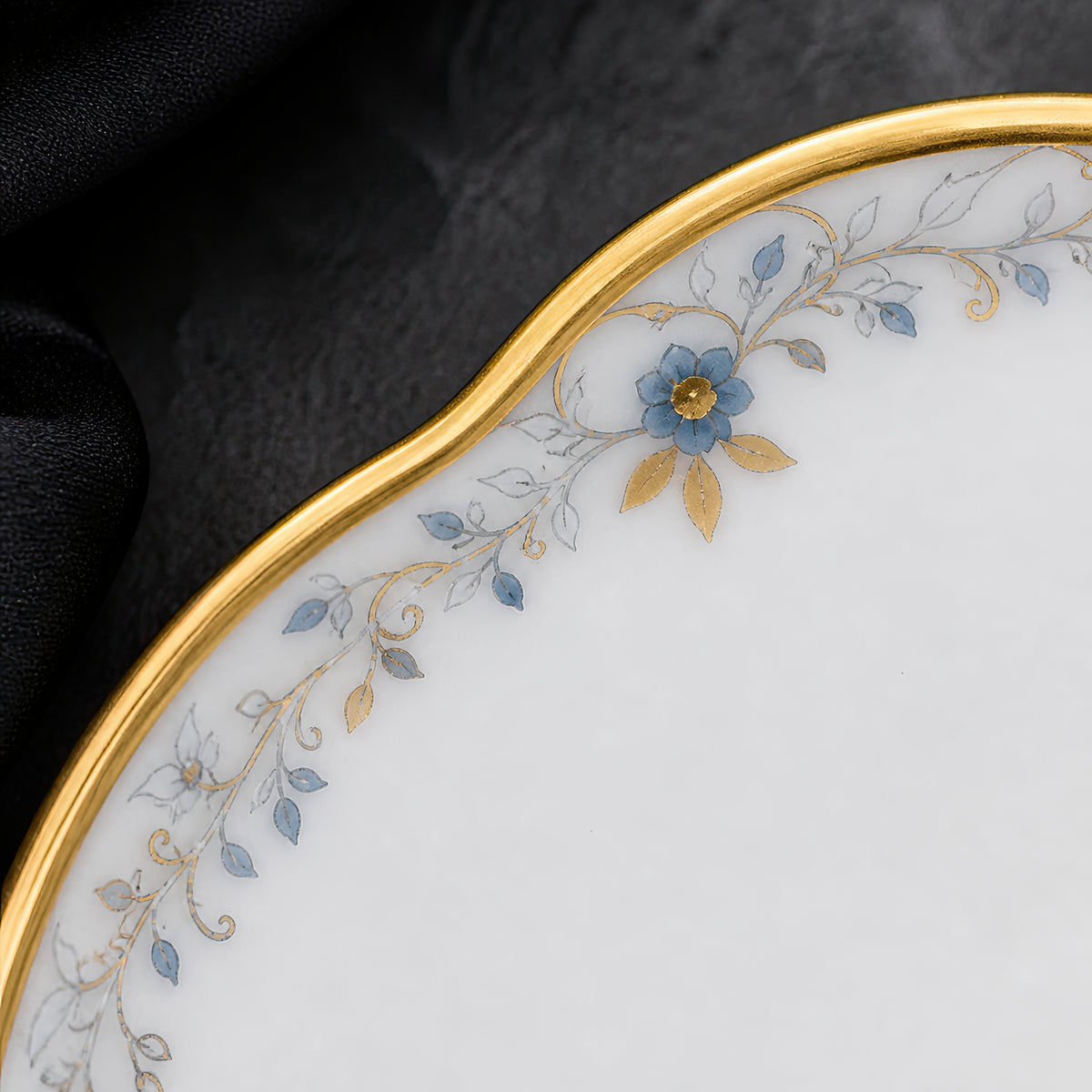 Close-up of the Valesse Azure petit dish showing its scalloped rim, fine gold latticework and small blue accents.