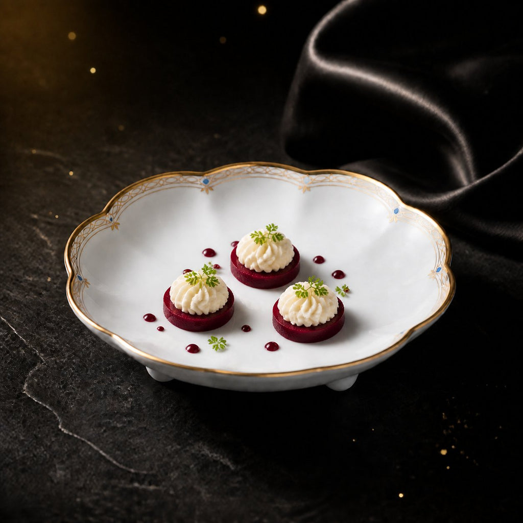 Valesse Azure 9.1 cm petit dish with three petite cream-topped desserts, showing the scalloped blue-and-gold rim.