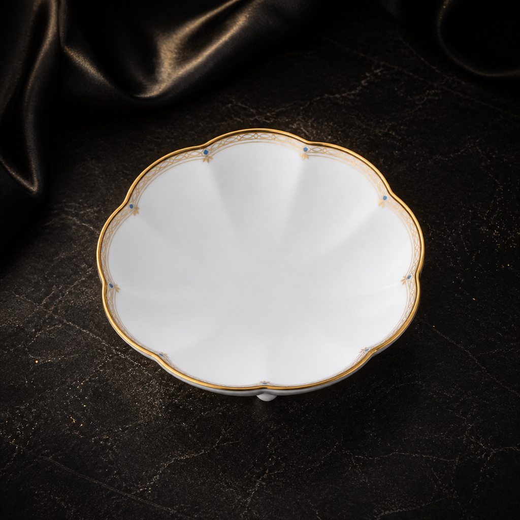 High-angle view of the empty Valesse Azure petit dish, showing the white bone china, scalloped shape and delicate blue-and-gold border.